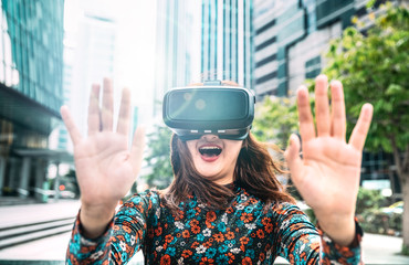 Young asian woman experiencing vr glasses in modern city - Virtual reality and wearable tech concept with girl having fun with headset goggles - Generation z digital trends on bright contrast filter