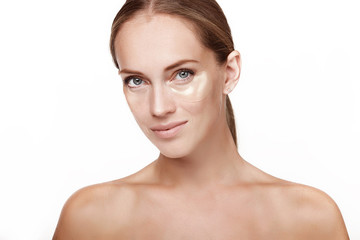 A beautiful young girl, after the shower, dresses face patches. Spa, facial skin care. In the studio on a white background.