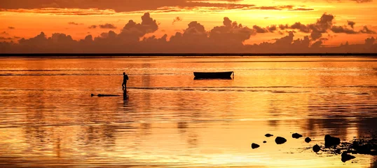 Crédence de cuisine en verre imprimé Le Morne, Maurice Coucher de soleil sur l& 39 île Maurice avec la silhouette d& 39 un pêcheur méconnaissable rentrant chez lui après une journée de pêche - Wanderlust et concept de voyage sur filtre orange du soleil