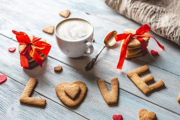Cup of coffee and a message from a sweet cookie in the form of the word love. Romantic Valentine's day gift