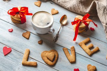 Fototapeta na wymiar Cup of coffee and a message from a sweet cookie in the form of the word love. Romantic Valentine's day gift