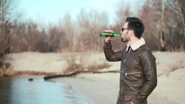 Relaxed Handsome Man Drinking Beer.Calm Peaceful Young Bearded Man In Sunglasses Stress Free Relaxing On Nature.Cheerful Man Celebrating And Drinking Cold Beer Outdoors From Bottle Enjoying Sunset.