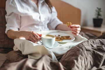 Woman have a romantic Breakfast in cozy morning bed. Coffee and word love from cookies. Surprise on Valentine's day