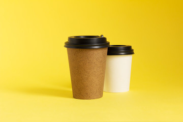 Take-away coffee cups on yellow background. Two coffee to go cups, mockup. 