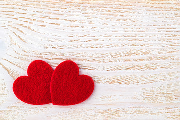 Naklejka na ściany i meble Two red felt valentine hearts on a white wood textured surface. Valentine greeting card with copy space. Romance and love concept.