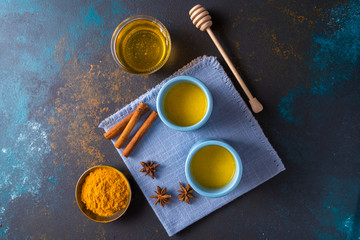 Ayurvedic golden turmeric latte milk  tea made with turmeric and other spiceson blue background. Flat lay.