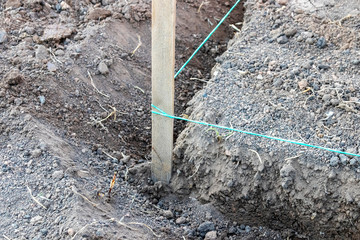 Marking peg with a stretched color rope in the summer garden under reconstruction