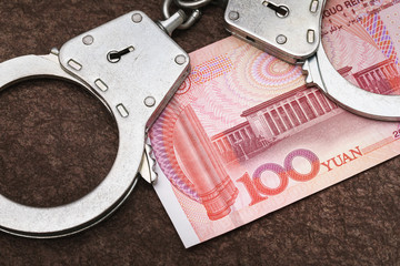 One hundred yuan and handcuffs on the table. The concept of illegal currency transactions