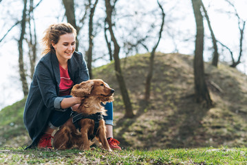 Candid photo of attractive young curly woman with her brown cocker spaniel posing in the park
