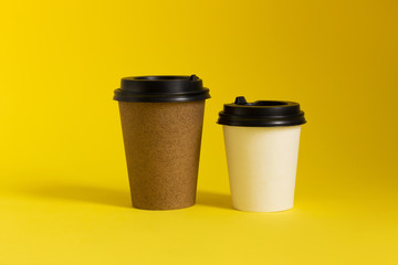 Coffee to go paper cups with lids on yellow background. Take-away coffee cups mockup.