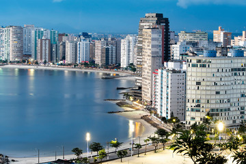Urbanized coast, tall buildings near to the beach of a coastal city at dusk, when city lights begin to turn on. Paulista coast, Sao Vicente city - SP Brazil.