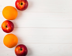 Autumn harvest, red apples and oranges on a white wooden background. Cozy autumn border. Thanksgiving day concept. Top view.