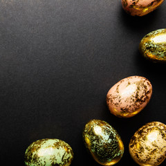 Natural Golden Speckled Easter Eggs of pastel colors on black background. Happy Easter card concept, minimalistic design, copy space