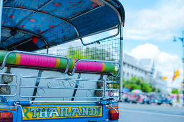 asia local travel in city activity with close up backside of local taxi (tuk tuk) with driver and tourism drive on street of bangkok Thailand with grandpalace landmark background