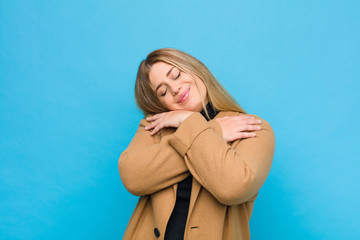 young blonde woman feeling in love, smiling, cuddling and hugging self, staying single, being...