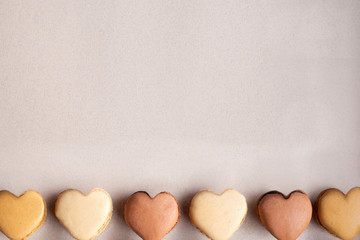 Colorful heart-shaped macaroons in a row on pastel background