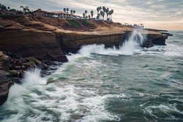 Long exposure surf crashing against beach bluffs on a cloudy day