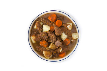 Irish beef stew with carrots and potatoes isolated on white background. Top view
