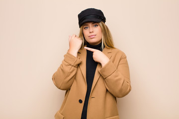 young blonde woman looking impatient and angry, pointing at watch, asking for punctuality, wants to...