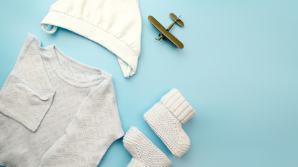 Flatlay of newborn baby boy clothes. Kit of dress for baby on blue background. Copy space.	