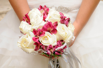 Ramo de rosas blancas y lirios de color rosa en las manos de una novia