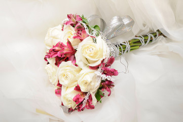 Ramo de rosas blancas y lirios de color rosa sobre el vestido de una novia