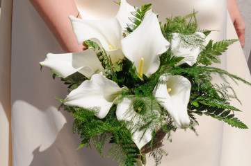Fototapeta na wymiar Elegante ramo de flores de alcatraz blanco en la mano de una novia