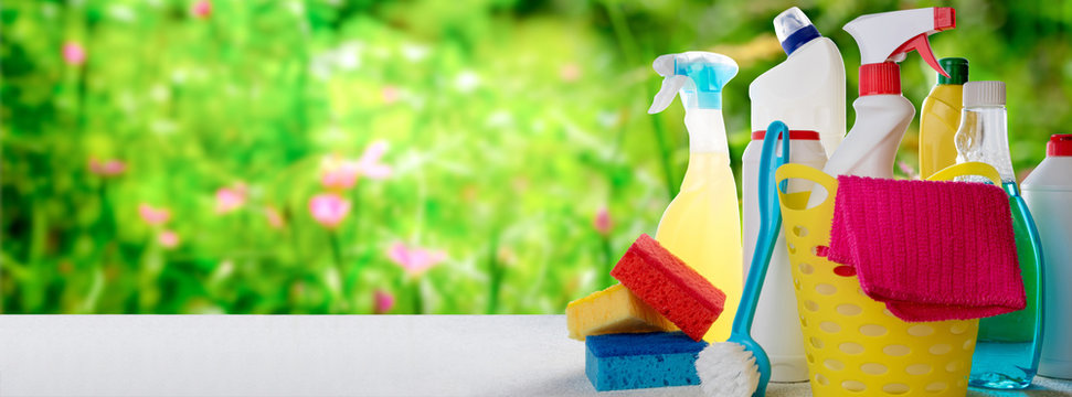Basket with cleaning service products on blurry nature background. Spring cleaning, eco natural cleaning products concept. Copy space