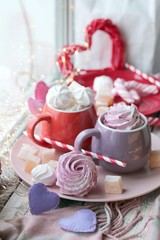 Fototapeta na wymiar Two cups of coffee with meringues and marshmallows, Turkish delight on a plate, hearts, illumination, against the background of a window, homeliness, Valentine's day, romantic greeting, happy birthday