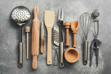 Flat lay kitchen tools and utensils on a gray concrete background, toned. Top view. Kitchenware is...