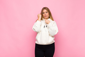 young blonde woman looking impatient and angry, pointing at watch, asking for punctuality, wants to...