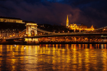 Fototapeta na wymiar Night View Of Szechenyi Bridge. Famous Chain Bridge Of Budapest. Beautiful lighting and reflection in the Danube River.