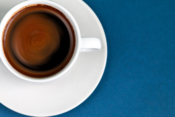 Black coffee espresso in white cup and saucer, blue color background with empty space for text, unhealthy food concept  