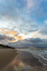 wide beach of the Baltic Sea in winter under a sunset cloudy sky at long exposure at dusk