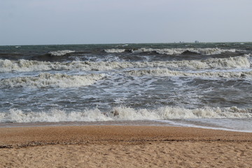 waves during a storm at sea. in the distance you can see large ships and barges