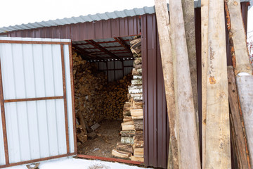 Harvested firewood for the winter in a new barn in the yard.