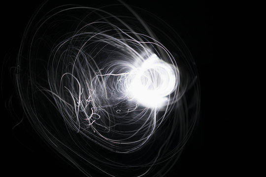 Creative, abstract spinning white spark on black background