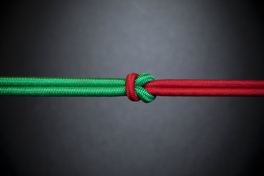 Red and green rope knotted in teamwork, unity