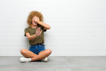 young afro woman covering face with hand and putting other hand up front to stop camera, refusing...