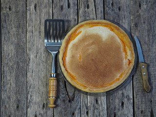 Round homemade pie with pumpkin, chopped walnuts, dipped in beaten eggs with sugar. Wooden rustic background. Homemade baking.
