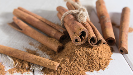 close-up, ground cinnamon with whole sticks on a white wooden table
