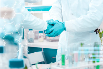 Closeup scientists hands in gloves making handshake at microbiology laboratory. Biotechnologists are congratulating each other after successful research, experiments, tests. Biologist workplace.