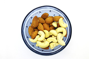 Fresh Mixed Almonds and Cashew nuts in a blue bowl, Top view. White isolated background.
