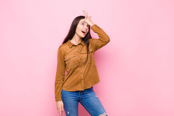 young pretty woman raising palm to forehead thinking oops, after making a stupid mistake or...