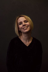 Woman is smiling on a dark background.