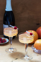 Champagne cocktail with grapefruit juice, garnished with zest and raspberries. Rustic style.