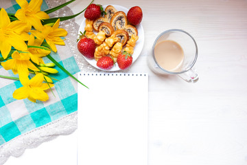 Coffee with sweets - pretzels with poppy seeds, fresh red strawberries and the inscription in the notebook: Good morning, my Love. The concept of Breakfast for Valentine's Day, love