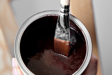 Protective acrylic varnish coating of wooden surface. Wood Finishing. Paintwork. A synthetic paint brush, in  a tin of brown color varnish