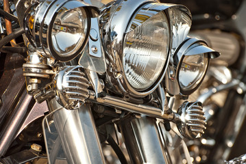 Motorcycles are placed in a row. Headlight closeup. Motorcycle chrome elements.