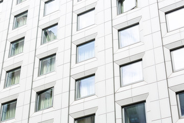 Exterior of modern commercial building. White wall with windows reflecting blue sky. Business center, skyscaper